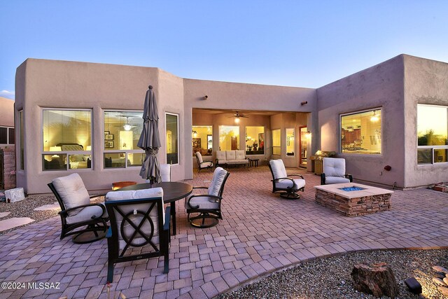 patio terrace at dusk featuring an outdoor living space with a fire pit and ceiling fan