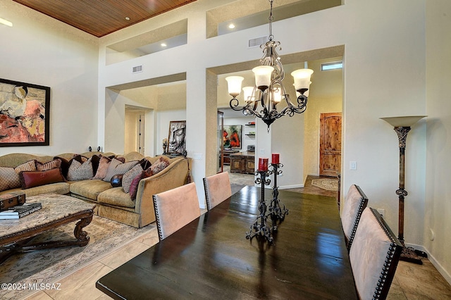 dining space with an inviting chandelier, a towering ceiling, and wooden ceiling