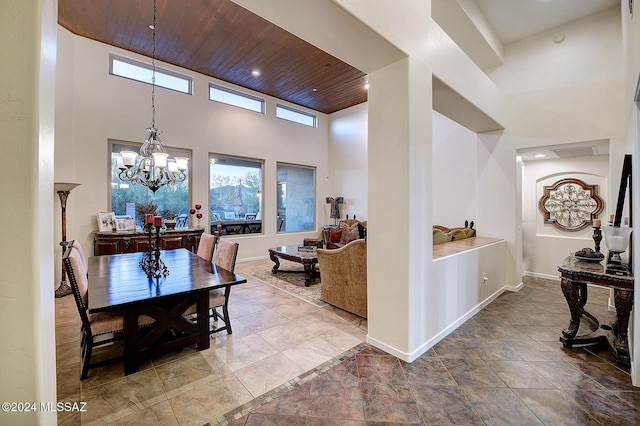 dining area with a high ceiling, a chandelier, and wood ceiling