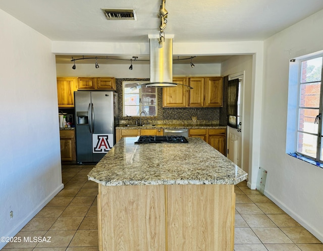 kitchen with stainless steel refrigerator with ice dispenser, island range hood, a kitchen island, light stone countertops, and backsplash