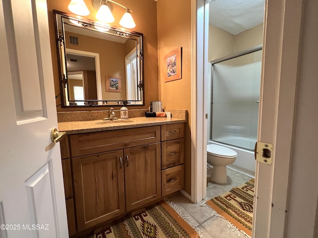 full bathroom featuring vanity, shower / bath combination with glass door, and toilet