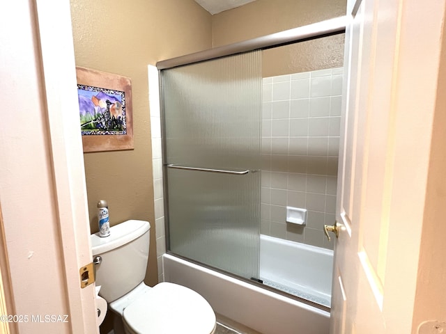 bathroom featuring shower / bath combination with glass door and toilet