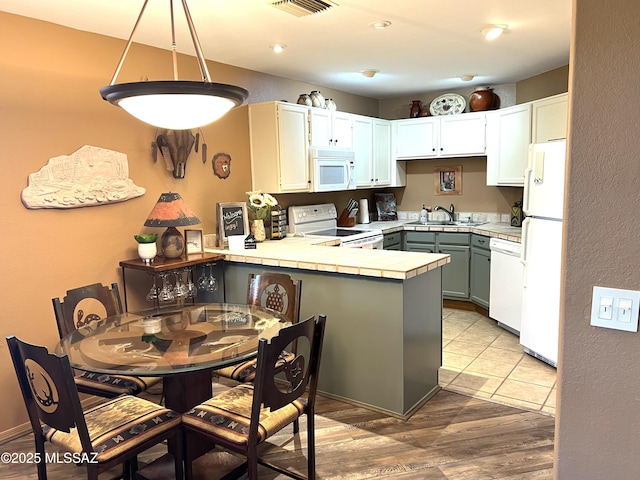 kitchen featuring sink, hanging light fixtures, kitchen peninsula, white appliances, and white cabinets