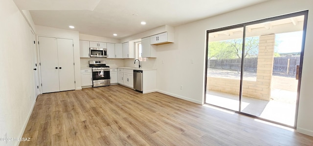 kitchen featuring white cabinetry, appliances with stainless steel finishes, sink, and light wood-type flooring