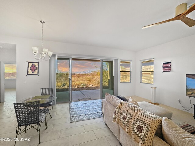 living room with ceiling fan with notable chandelier and light tile patterned floors