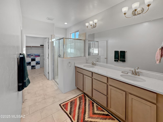 bathroom featuring a chandelier, a stall shower, and a sink