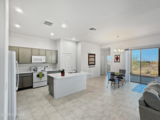 kitchen featuring visible vents, open floor plan, a sink, and white appliances