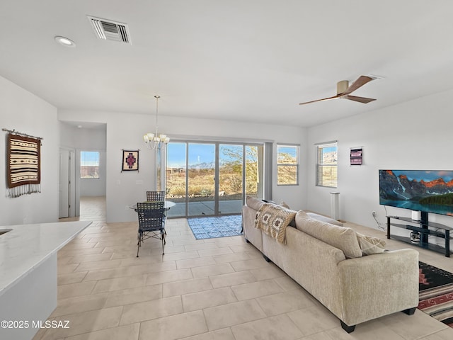 living room with ceiling fan with notable chandelier and plenty of natural light