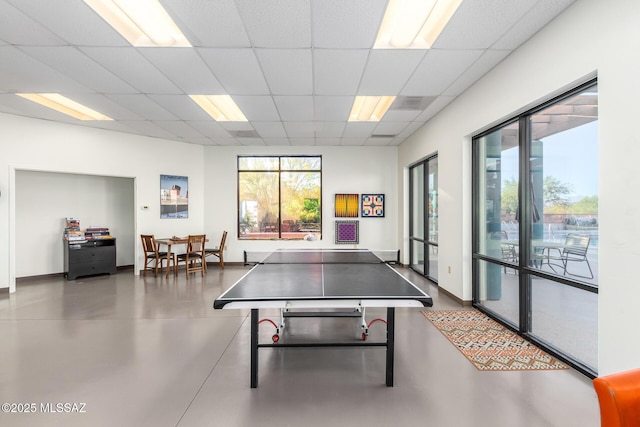 recreation room featuring a paneled ceiling and finished concrete flooring