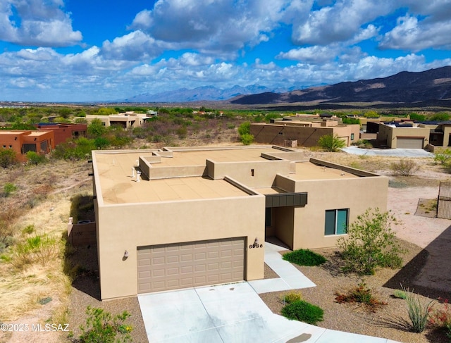 view of front of property featuring stucco siding, a mountain view, driveway, and a garage