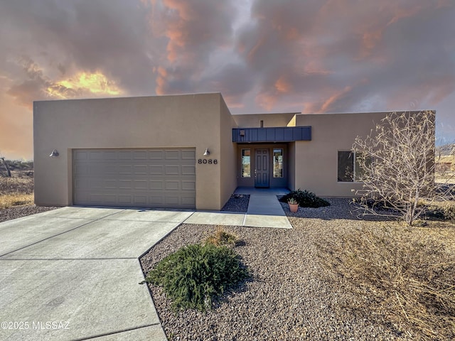 view of front facade featuring a garage, driveway, and stucco siding