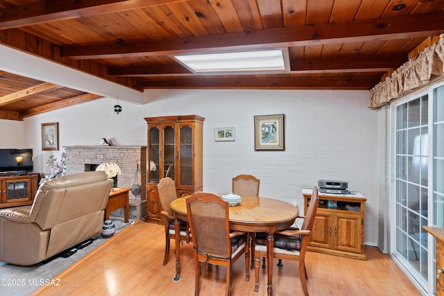 dining room with vaulted ceiling with beams, wood ceiling, a fireplace, and light wood-type flooring