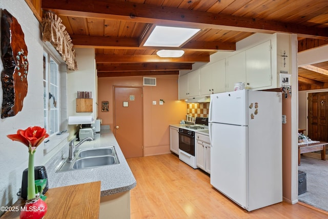 kitchen featuring white refrigerator, white cabinetry, sink, and gas stove