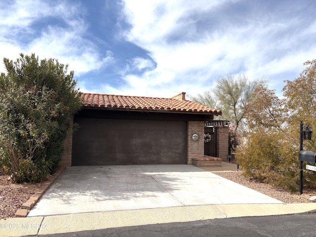 view of front facade featuring a tile roof, concrete driveway, brick siding, and a garage