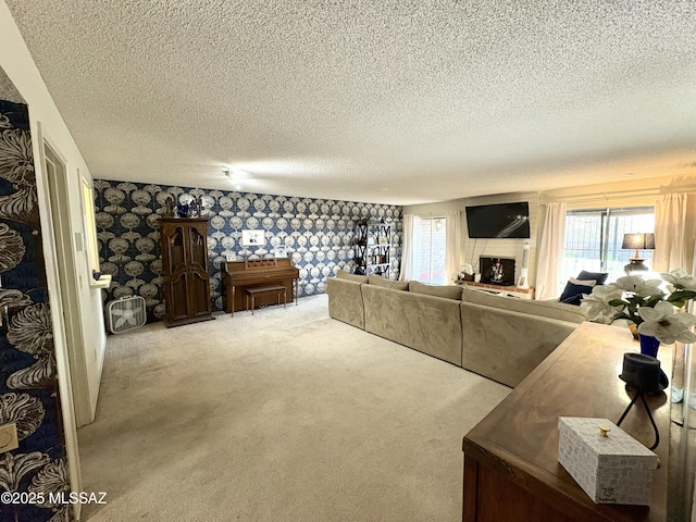 carpeted living room featuring a fireplace, wallpapered walls, and a textured ceiling