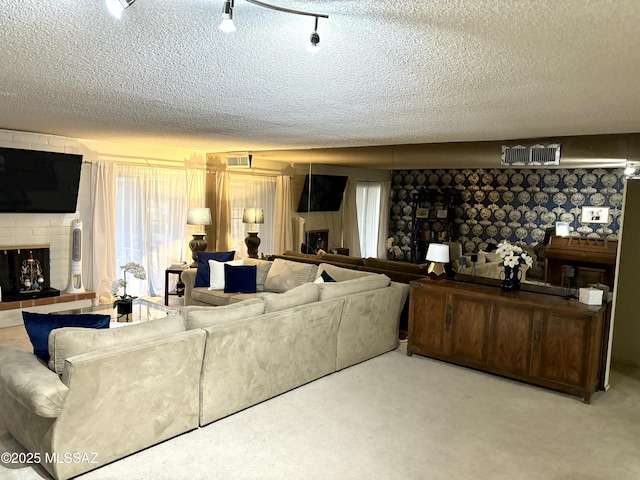 living area with a brick fireplace, a healthy amount of sunlight, carpet floors, and a textured ceiling