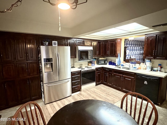 kitchen featuring a sink, stainless steel appliances, light wood-style floors, light countertops, and a raised ceiling