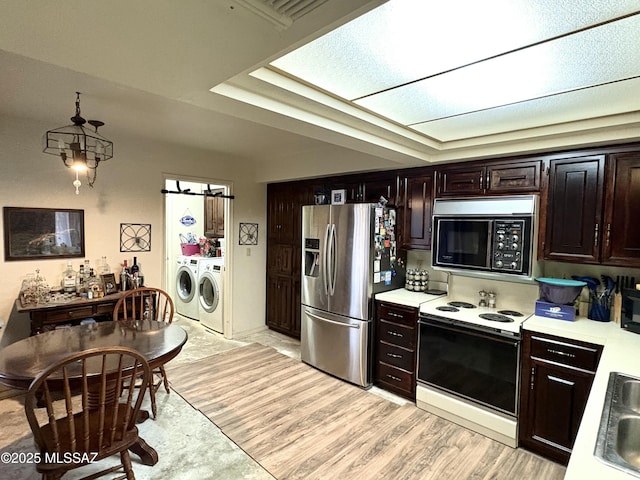 kitchen featuring black microwave, washer and clothes dryer, light countertops, electric stove, and stainless steel refrigerator with ice dispenser