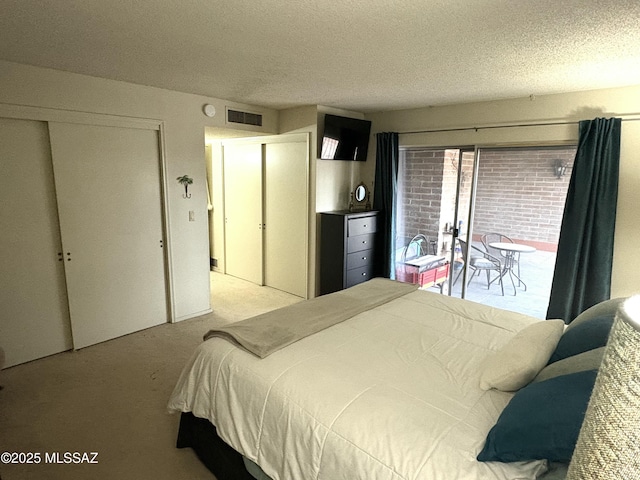 bedroom with access to exterior, visible vents, carpet floors, and a textured ceiling