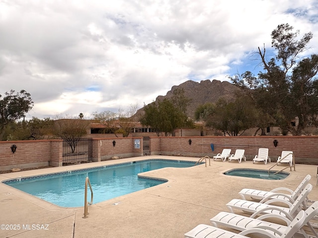 pool featuring fence, a community hot tub, and a patio area