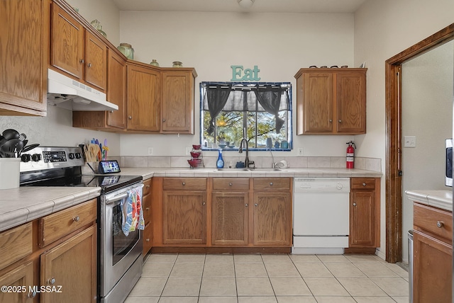 kitchen featuring light tile patterned flooring, sink, tile counters, electric range, and white dishwasher