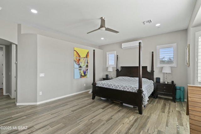 bedroom with ceiling fan, a wall mounted air conditioner, and wood-type flooring