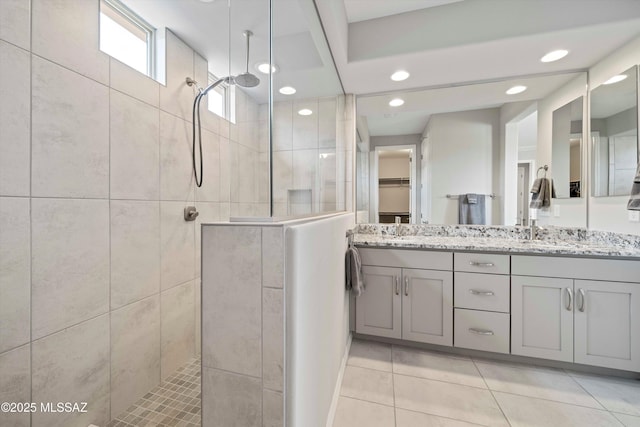 bathroom featuring vanity, a tile shower, and tile patterned floors