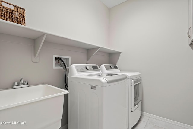 laundry area featuring cabinets, light tile patterned flooring, sink, and washing machine and clothes dryer