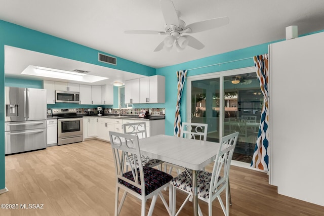 dining space with sink, ceiling fan, and light wood-type flooring