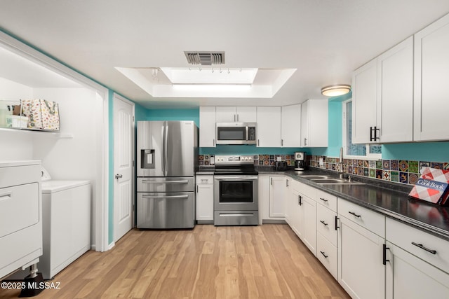 kitchen featuring white cabinetry, a skylight, independent washer and dryer, and appliances with stainless steel finishes