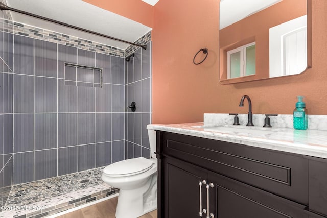 bathroom with vanity, tiled shower, and toilet