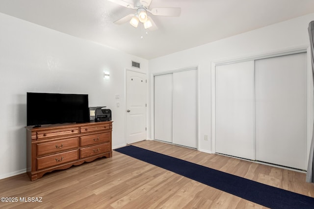 bedroom with multiple closets, ceiling fan, and light hardwood / wood-style floors