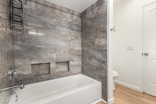 bathroom with tiled shower / bath, hardwood / wood-style flooring, and toilet