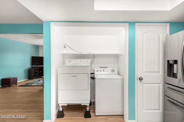 laundry room featuring washing machine and dryer and light wood-type flooring