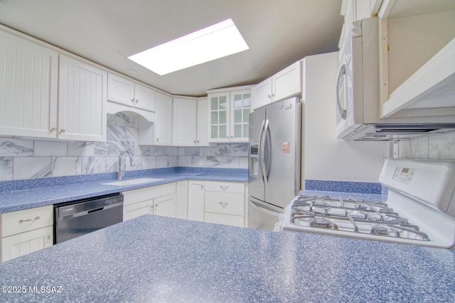 kitchen with a sink, tasteful backsplash, glass insert cabinets, and white appliances