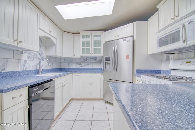 kitchen with white cabinets, a sink, a skylight, and white appliances