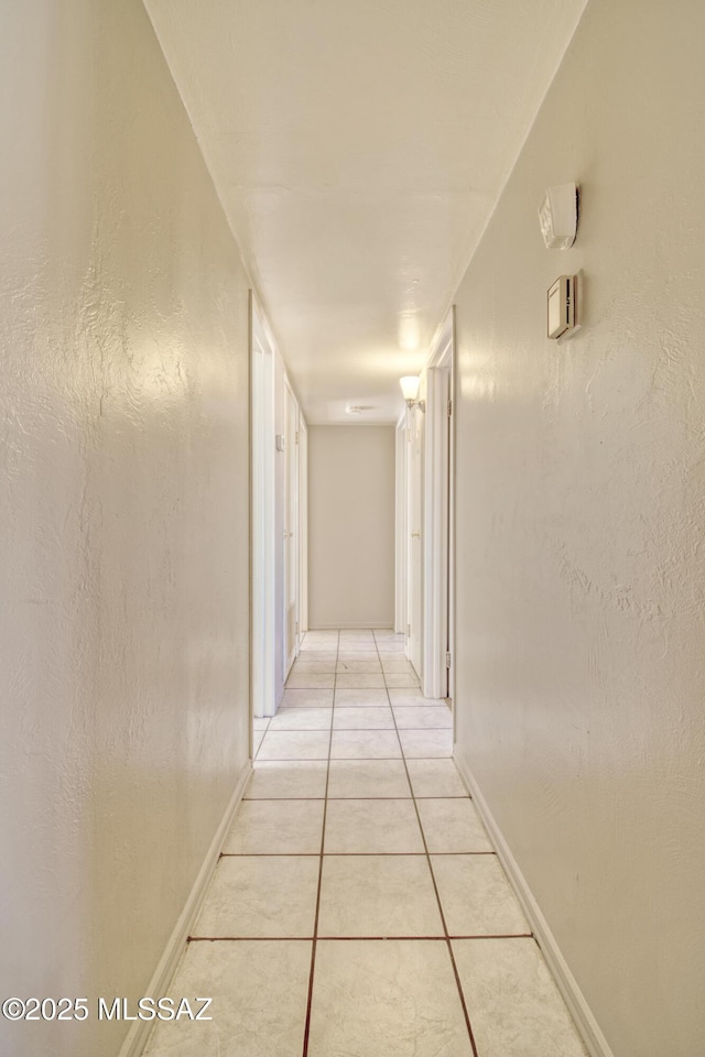 corridor with light tile patterned floors and baseboards