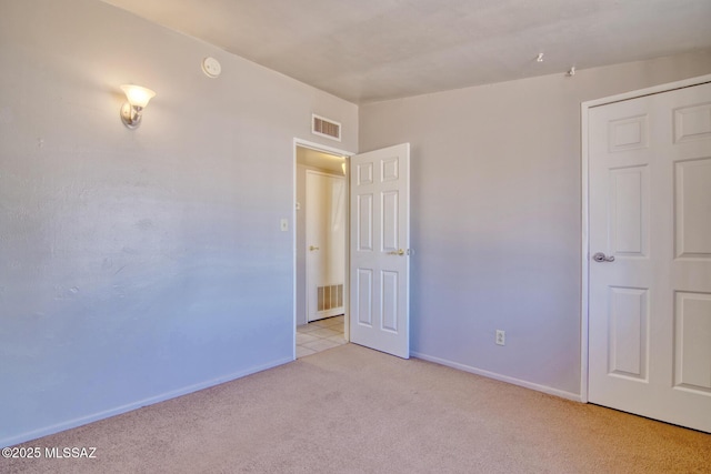 empty room with baseboards, lofted ceiling, visible vents, and light carpet