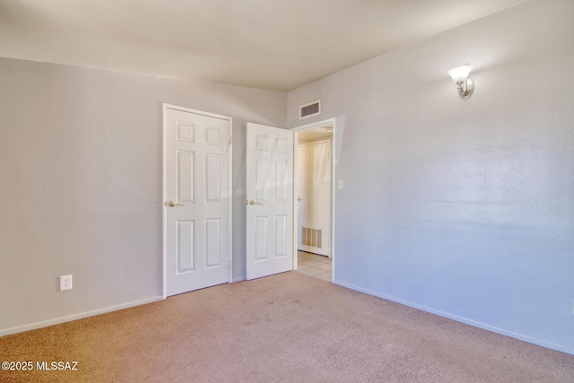 unfurnished bedroom featuring baseboards, visible vents, and light carpet