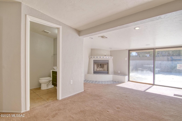 unfurnished living room featuring visible vents, a tiled fireplace, and carpet floors
