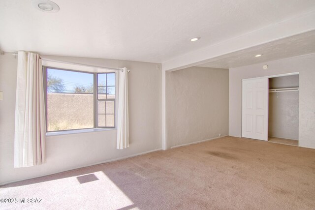 unfurnished bedroom with light colored carpet and lofted ceiling