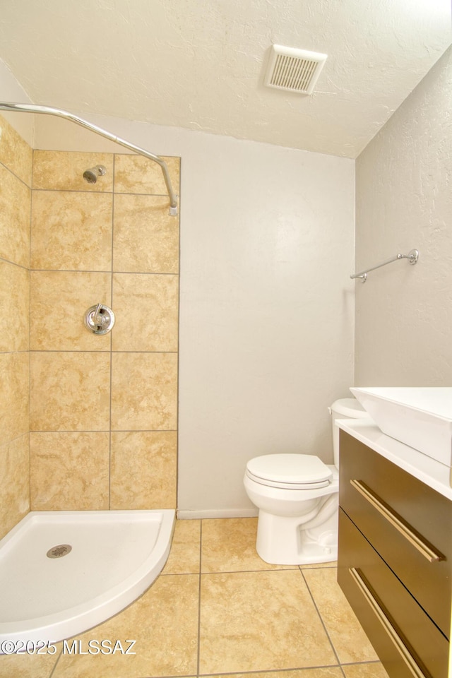 bathroom featuring tile patterned floors, toilet, tiled shower, and visible vents