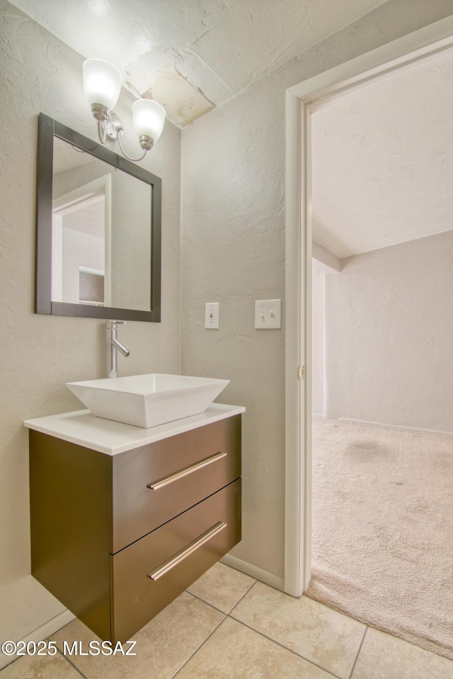 bathroom with tile patterned floors, a textured wall, and vanity