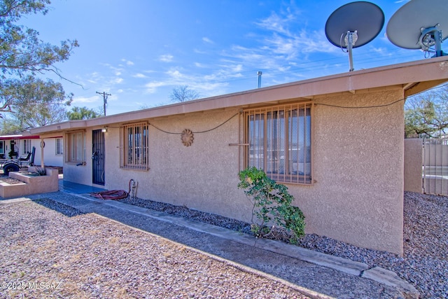 view of front facade with stucco siding and fence