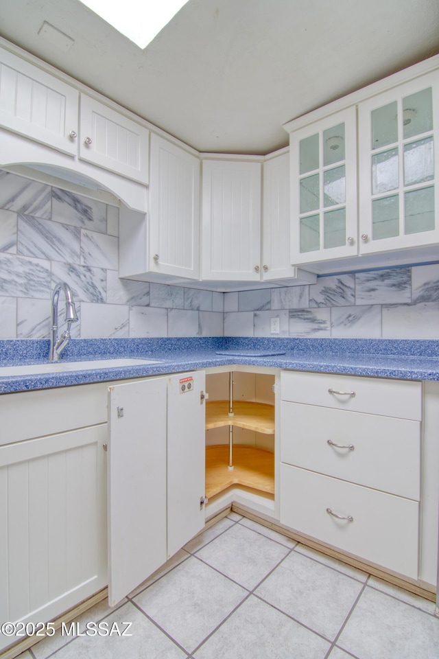 kitchen with decorative backsplash, glass insert cabinets, white cabinets, and a sink