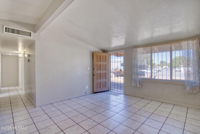 unfurnished room with vaulted ceiling, visible vents, baseboards, and light tile patterned floors