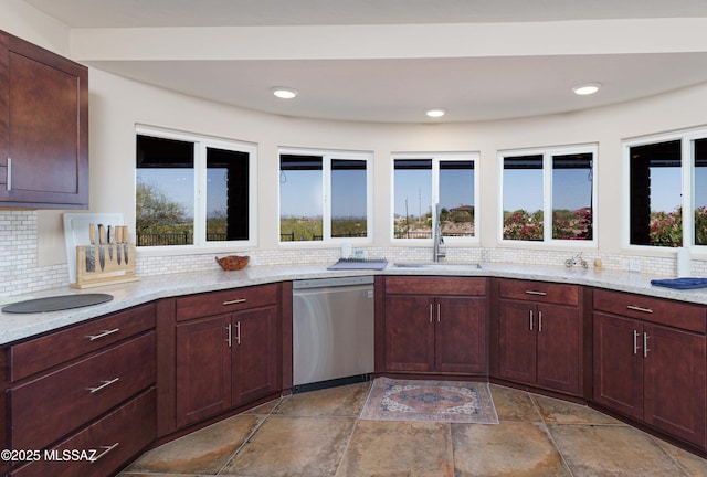 kitchen with tasteful backsplash, dishwasher, sink, and light stone countertops