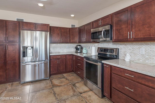 kitchen featuring light stone counters, stainless steel appliances, and backsplash