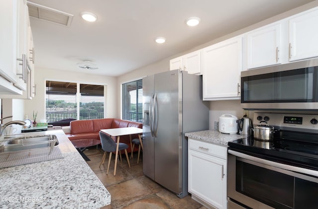 kitchen with sink, stainless steel appliances, white cabinets, and light stone countertops