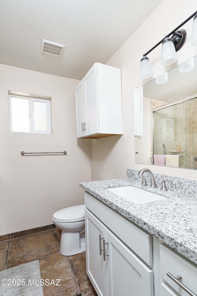 bathroom with vanity, toilet, and a shower with door